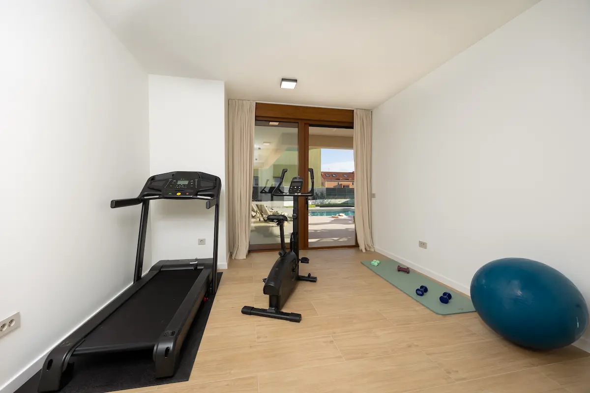 A gym equipped with a treadmill, a bicycle, and dumbbells.